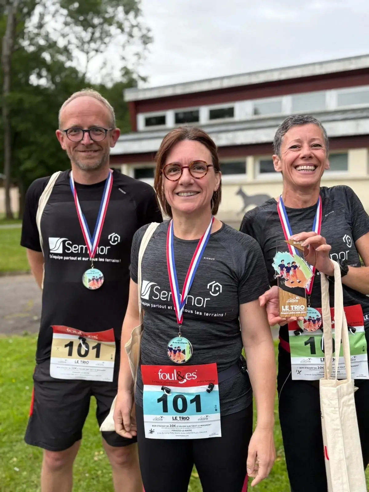 Trois employés portant une médaille d'une course à pied