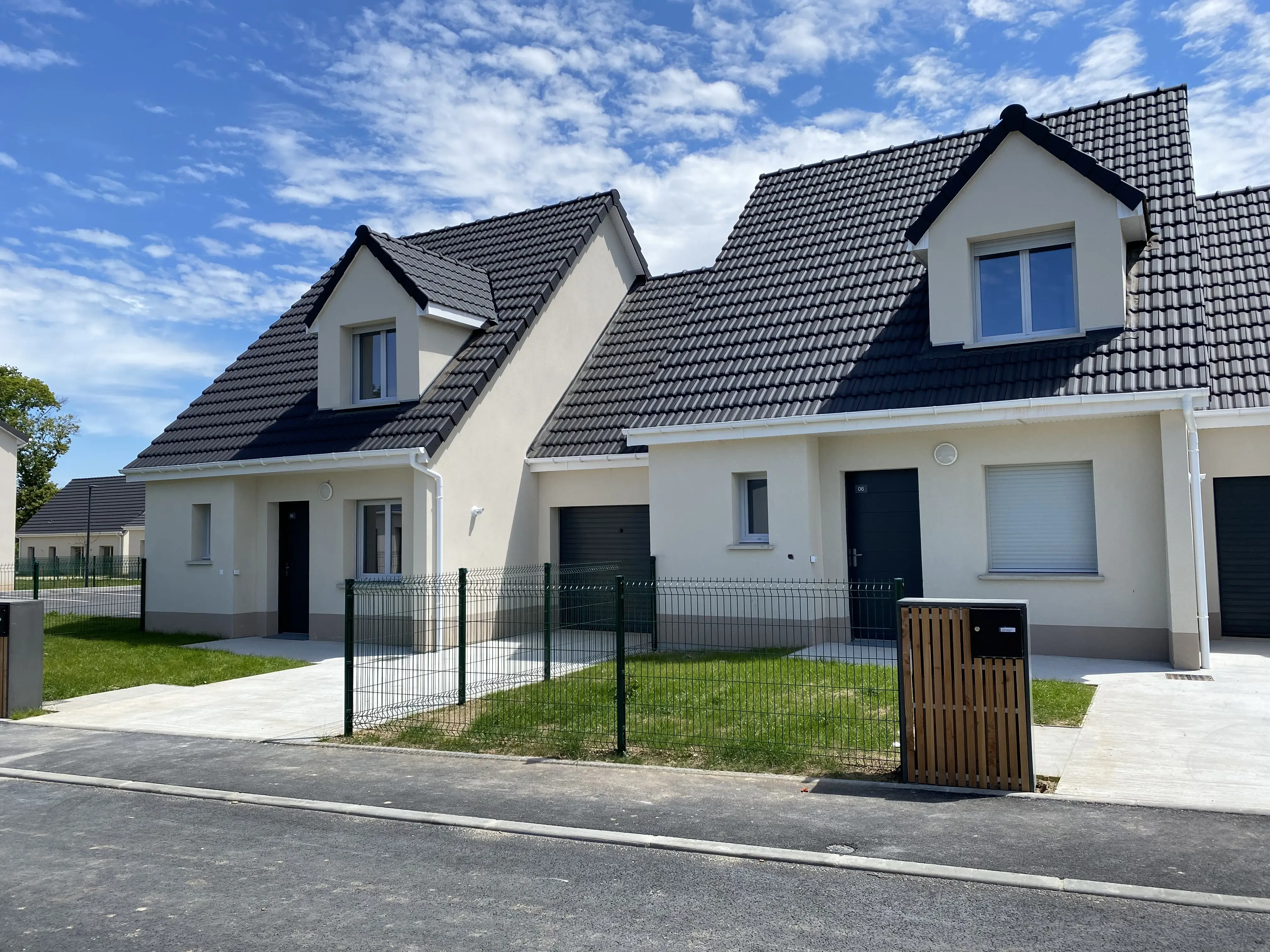 Deux maisons mitoyennes vue de devant avec leur garage et une allée blanche