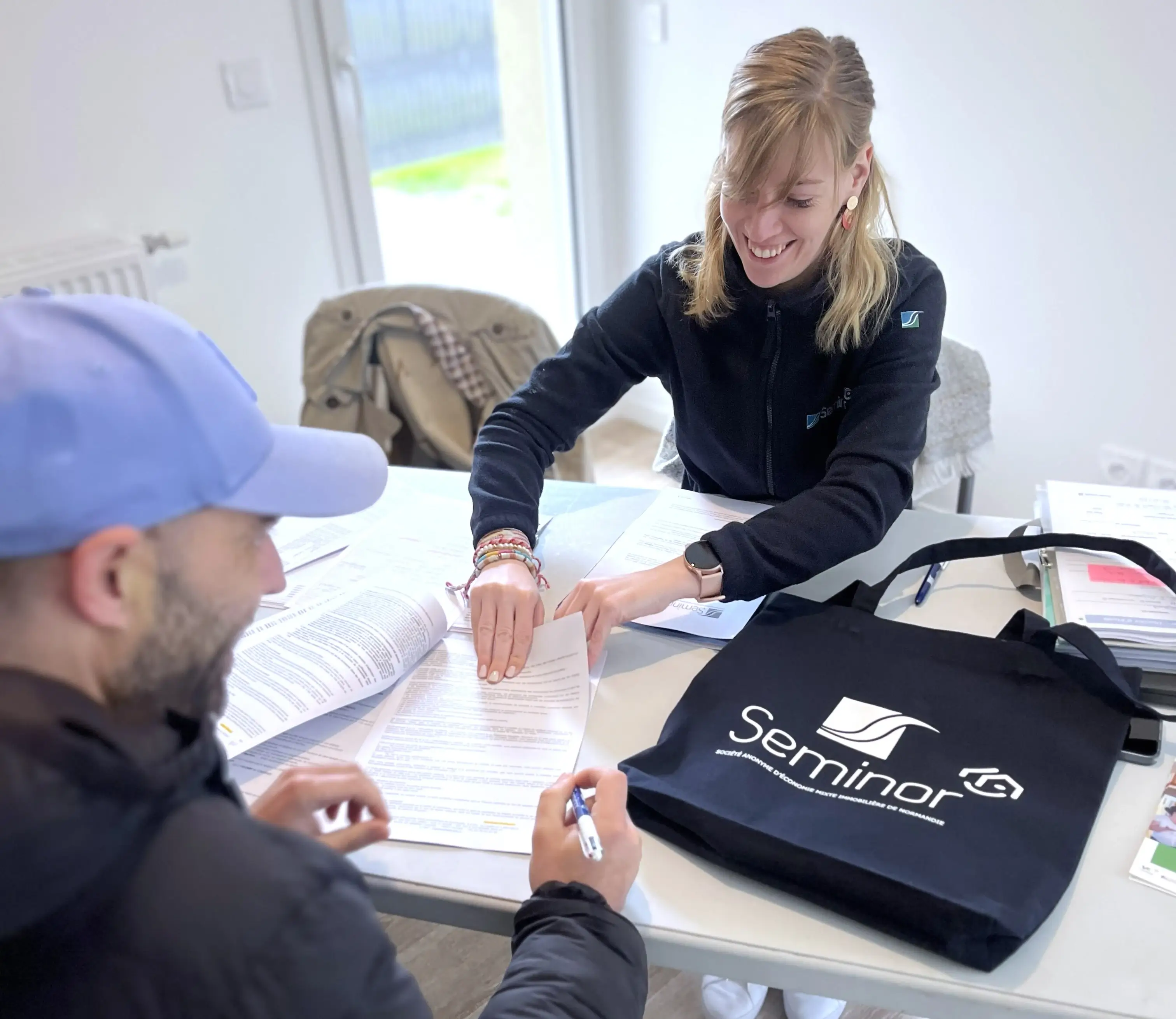 Deux personnes autour d'une table dans un appartement signant un contrat de mise en habitation