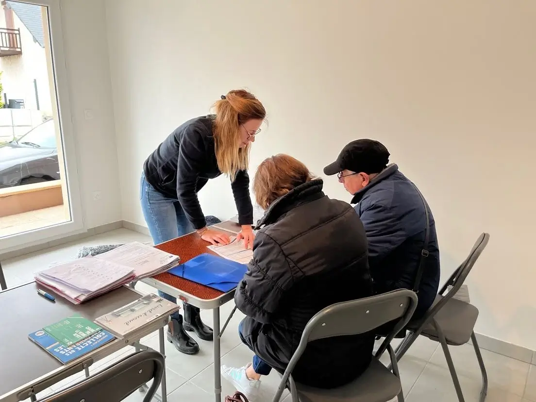 Trois personnes autour d'une table qui signe un contrat de mise en habitation