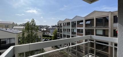 Balcon abrité avec le balcon du dessus, vue sur l'entreprise Seminor, sur la résidence ainsi que sur le passage du train et la rue de l'inondation, balcon avec rambarde en aluminium et plaque en verre exposé plein sud