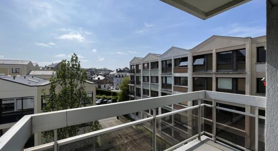 Balcon abrité avec le balcon du dessus, vue sur l'entreprise Seminor, sur la résidence ainsi que sur le passage du train et la rue de l'inondation, balcon avec rambarde en aluminium et plaque en verre exposé plein sud