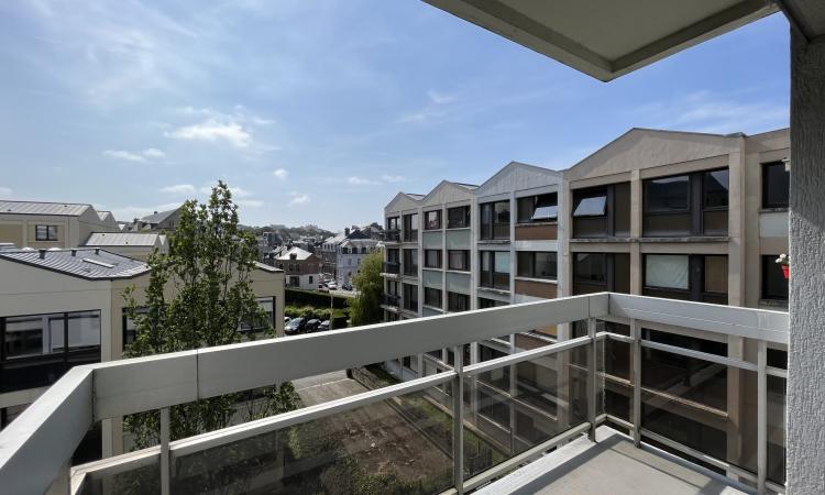 Balcon abrité avec le balcon du dessus, vue sur l'entreprise Seminor, sur la résidence ainsi que sur le passage du train et la rue de l'inondation, balcon avec rambarde en aluminium et plaque en verre exposé plein sud